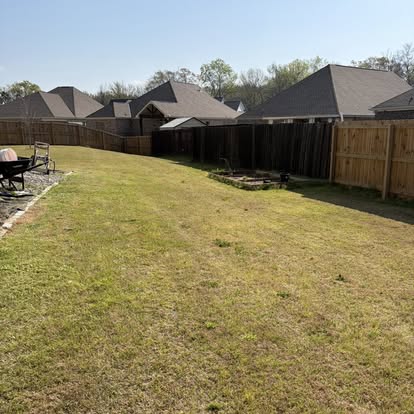 Wide manicured backyard freshly mowed with privacy fence